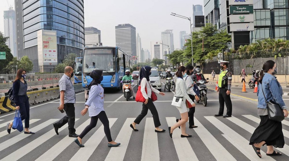 People wearing a face mask as a precaution against the new coronavirus outbreak, walk on a pedestrian crossing at the main business district in Jakarta, Indonesia,. (AP Photo)