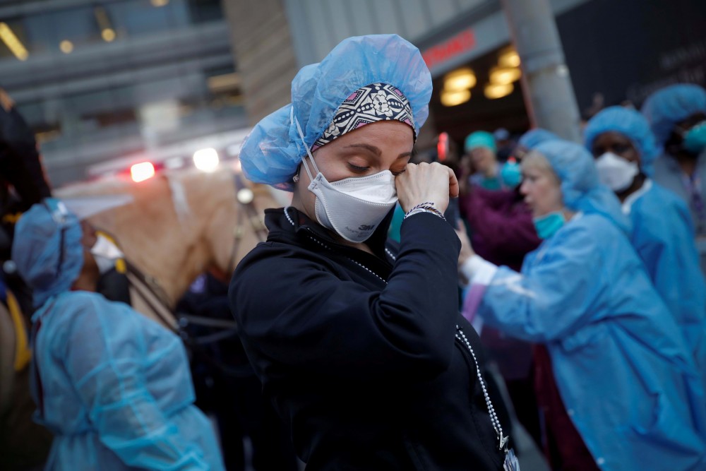 A nurse wipes away tears as she stands outside NYU Langone Medical Center on 1st Avenue in Manhattan as New York Police Department (NYPD) Mounted Police and other units came to cheer and thank healthcare workers at 7pm during the outbreak of the coronavirus disease (COVID-19) in New York City, Mike Segar | Reuters