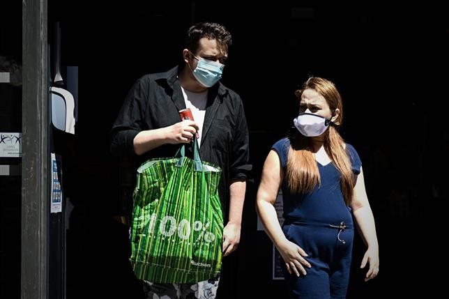 A man and a woman wearing protective face masks due to the COVID-19 coronavirus pandemic, walk out of a shop in Bordeaux, southwestern France. AFP