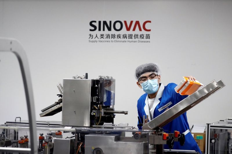 FILE PHOTO: A man works in the packaging facility of Chinese vaccine maker Sinovac Biotech, developing an experimental coronavirus disease (COVID-19) vaccine, during a government-organized media tour in Beijing, China, September 24, 2020. REUTERS/Thomas Peter/File Photo