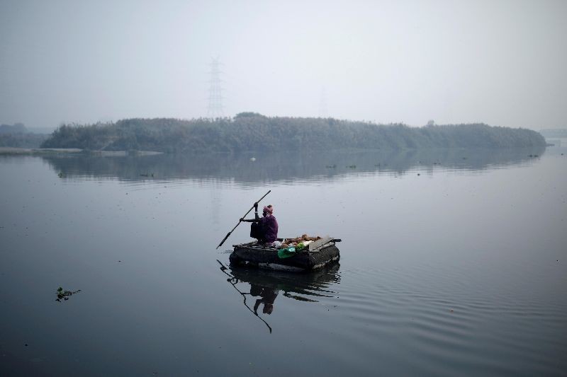 A man rows a makeshift boat across Yamuna river on a smoggy morning in New Delhi, India. (Photo by Adnan Abidi/Reuters)