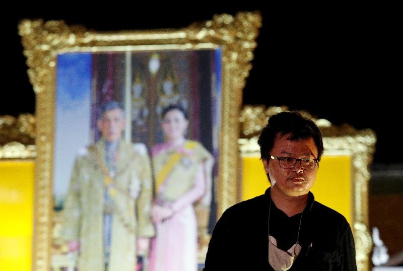 Anon Nampa, one of the leaders of recent anti-government protests, is seen near a portrait of Thailand's King Maha Vajiralongkorn and Queen Suthida after a rally to demand the government to resign, to dissolve the parliament and to hold new elections under a revised constitution, in Bangkok, Thailand, August 16, 2020. REUTERS/Jorge Silva/File Photo