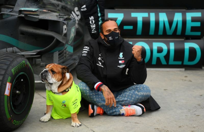 Mercedes' Lewis Hamilton poses with his dog as he celebrates after winning the race and the world championship Pool via REUTERS/Clive Mason