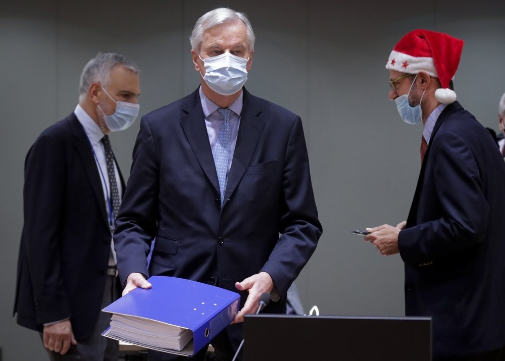 A colleague wears a Christmas hat as European Union chief negotiator Michel Barnier, center, carries a binder of the Brexit trade deal during a special meeting of Coreper, at the European Council building in Brussels, Friday, Dec. 25, 2020. European Union ambassadors convened on Christmas Day to start an assessment of the massive free-trade deal the EU struck with Britain. After the deal was announced on Thursday, EU nations already showed support for the outcome and it was expected that they would unanimously back the agreement, a prerequisite for its legal approval. (AP/PTI Photo)