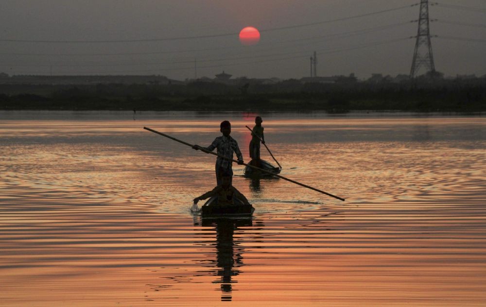 Siliguri: Two men sail their boats across a river during the last sunset of the year 2020, in Siliguri, Thursday, Dec. 31, 2020. (PTI Photo)