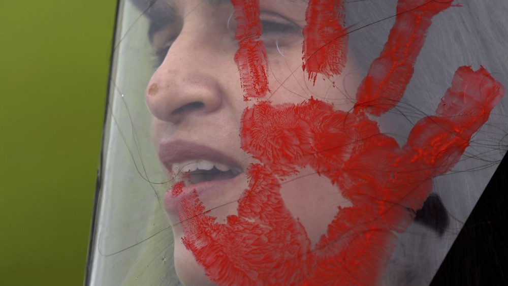 A demonstrator wears a face shield with a red handprint, mimicking blood, to protest Brazilian President Jair Bolsonaro's handling of the deadly coronavirus pandemic in Brasilia, Brazil. (AP Photo/Eraldo Peres)