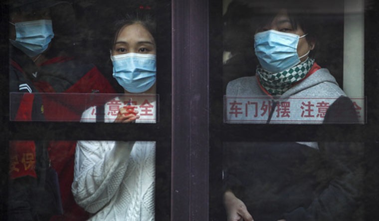 Commuters wearing face masks to help curb the spread of the coronavirus look out from a traveling bus during the morning rush hour in Beijing, Monday, Oct. 26, 2020. Schools and kindergartens have been suspended and communities are on lockdown in Kashgar, a city in China's northwest Xinjiang region, after more than 130 asymptomatic cases of the coronavirus were discovered | AP