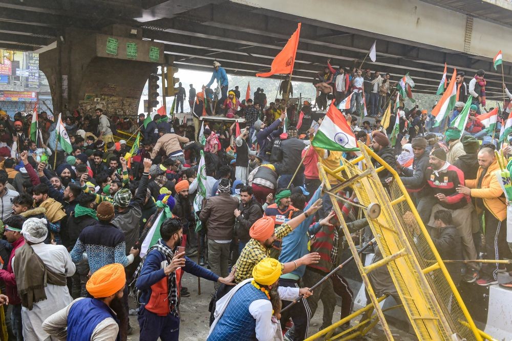 New Delhi: Farmers attempt to break a barricade near Nangloi as they participate in the 'Kisan Gantantra Parade', during their ongoing protest against Centre's farm reform laws, on the occasion of 72nd Republic Day, in New Delhi, Tuesday, Jan. 26,  2021. (PTI Photo/Kamal Kishore)