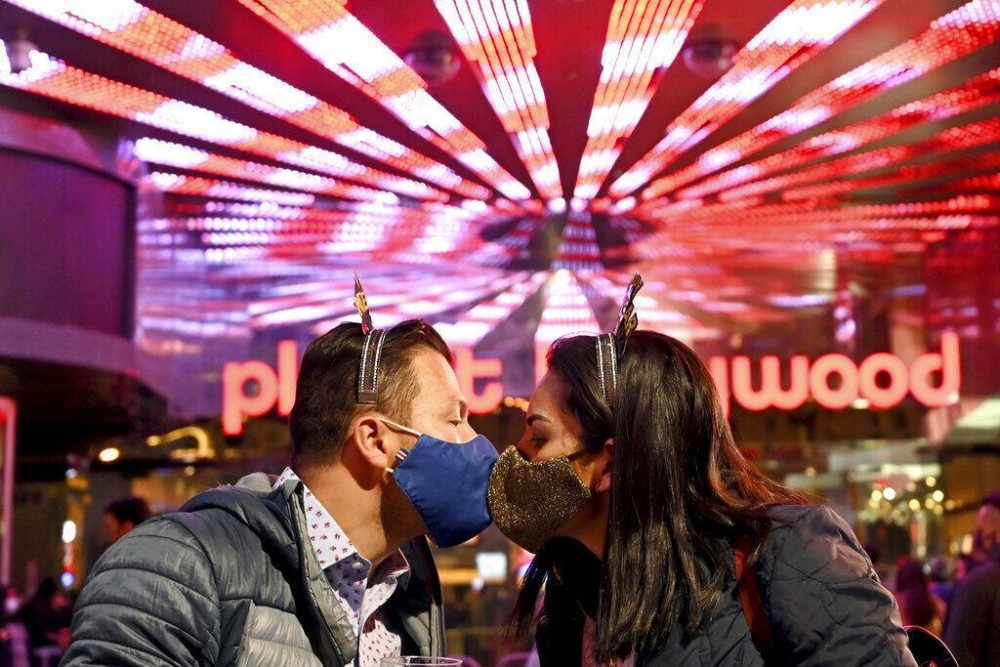 A couple wearing face masks kisses as they celebrate New Year's Eve along the Las Vegas Strip in Las Vegas. (AP Photo/David Becker) David Becker