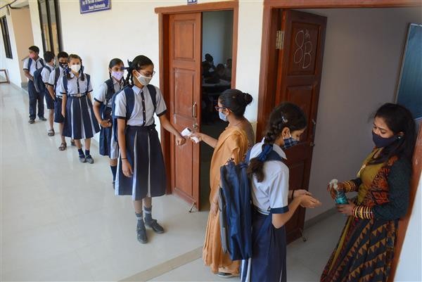Students undergo thermal scanning and get their hands sanitized as they arrive at a school that was reopened with certain COVID-19 safety guidelines, in Thane, on Tuesday, February 16, 2021. PTI