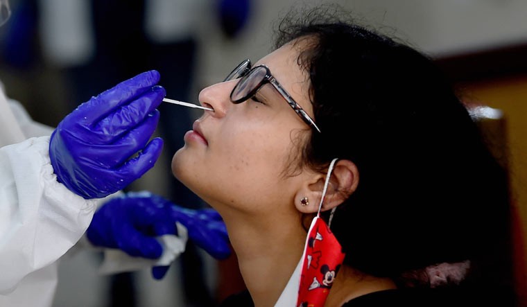 A medic collects a sample of a woman for COVID-19 test at NDMC Child welfare centre, in Sarojini Nagar, New Delhi | PTI