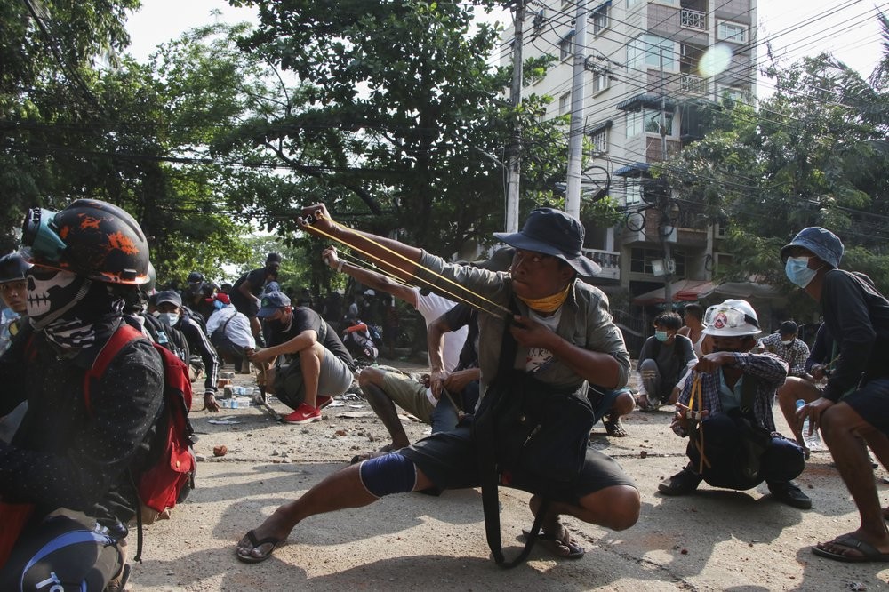 Anti-coup protesters use sling shot to confront police at Thaketa Township in Yangon, Myanmar, Sunday, March 28, 2021. Protesters in Myanmar returned to the streets Sunday to press their demands for a return to democracy, just a day after security forces killed more than 100 people in the bloodiest day since last month's military coup. (AP Photo)