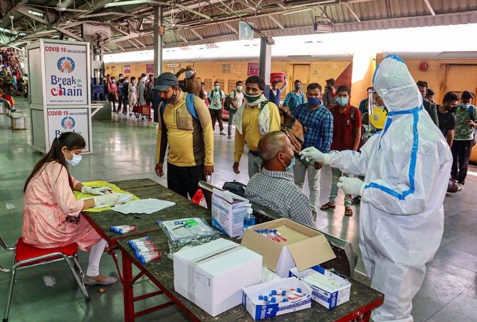 A health worker takes a nasal swab sample from a passenger for COVID-19 test, at a railway station in Jammu. Photograph: PTI Photo