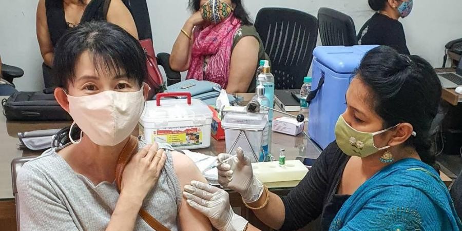 A medic administers the COVID-19 vaccine dose to a Japanese woman during a vaccination drive at IMT Industrial Association office, at Manesar in Gurugram district. (Photo | PTI)