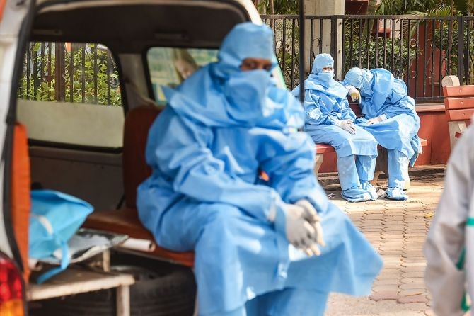 Family members, wearing PPE kits, wait during cremation of a COVID-19 victim, at the Nigambodh Ghat in New Delhi. Photograph: Arun Sharma/PTI Photo