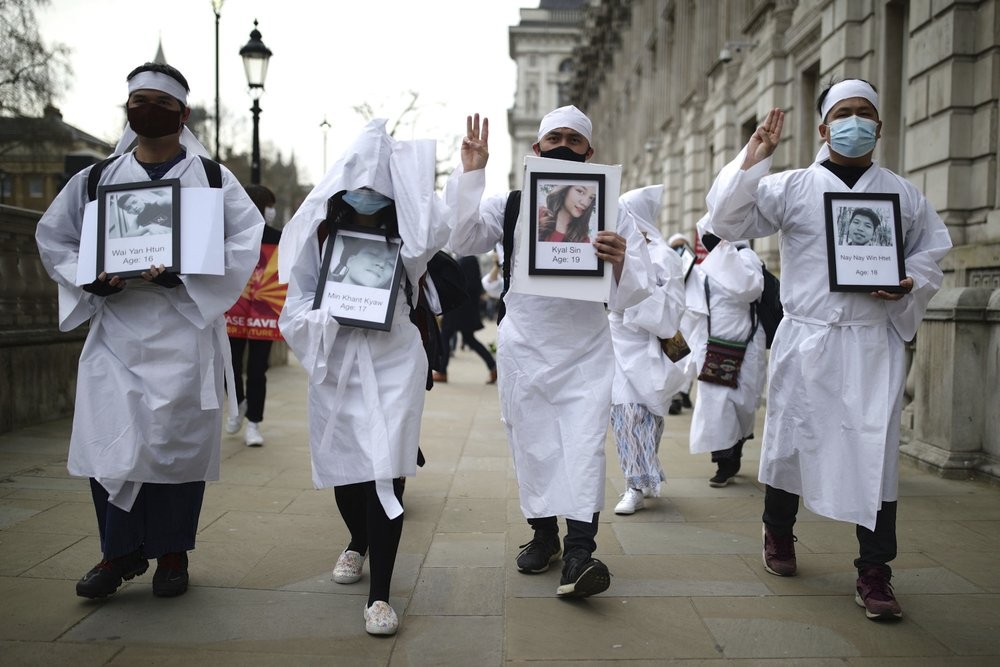 Protesters holding photos of protestors killed, as they march in Westminster, demonstrating against the Feb. 1 coup in Myanmar which ousted Aung San Suu Kyi's elected government, in London, Wednesday, March 31, 2021. (Aaron Chown/PA via AP)