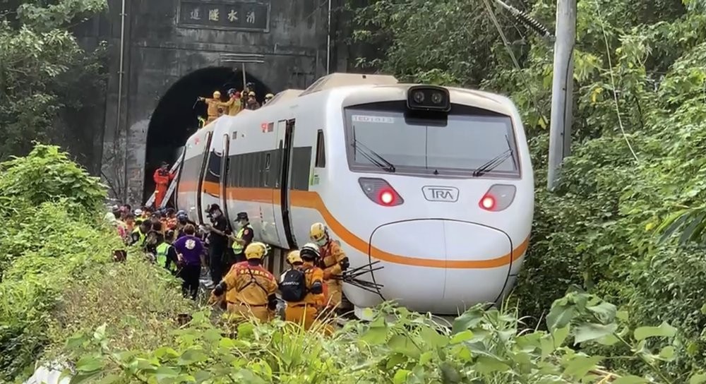 In this photo released by the Executive Yuan, rescue workers gather near one end of the train involved in a derailment near the Taroko Gorge area in Hualien, Taiwan on Friday, April 2, 2021. The train partially derailed in eastern Taiwan on Friday after colliding with an unmanned vehicle that had rolled down a hill, killing dozens. With the train still partly in a tunnel, survivors climbed out of windows and walked along the train's roof to reach safety after the country's deadliest railway disaster. (Executive Yuan via AP)