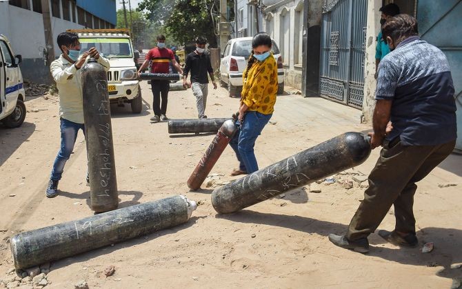 Relatives of COVID-19 patients move oxygen cylinders to get them refilled with medical oxygen in Gurugram. Photograph: Atul Yadav/PTI Photo