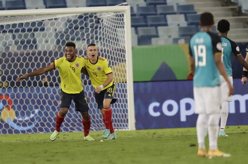Colombia's Rafael Borre, left, and Colombia's Miguel Borja celebrate the opening goal scored by Colombia's Edwin Cardona during a Copa America soccer match against Ecuador at Arena Pantanal stadium in Cuiaba, Brazil, Sunday, June 13, 2021. (AP Photo/Andre Penner)