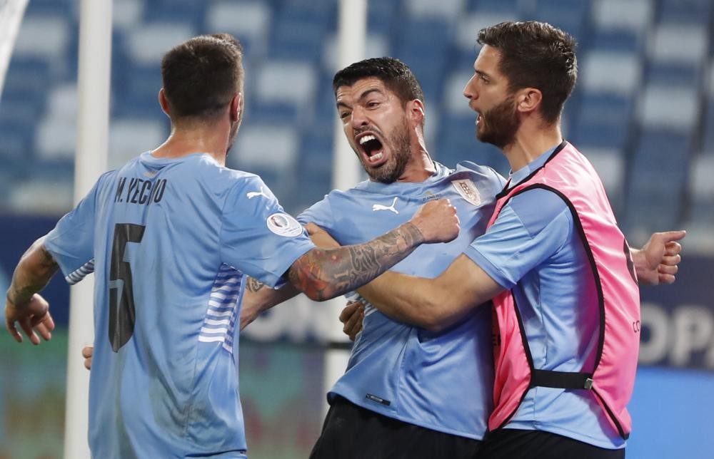 Uruguay's Luis Suarez, center, celebrates scoring his team's opening goal against Chile during a Copa America soccer match at Arena Pantanal stadium in Cuiaba, Brazil, Monday, June 21, 2021. (AP Photo/Andre Penner)