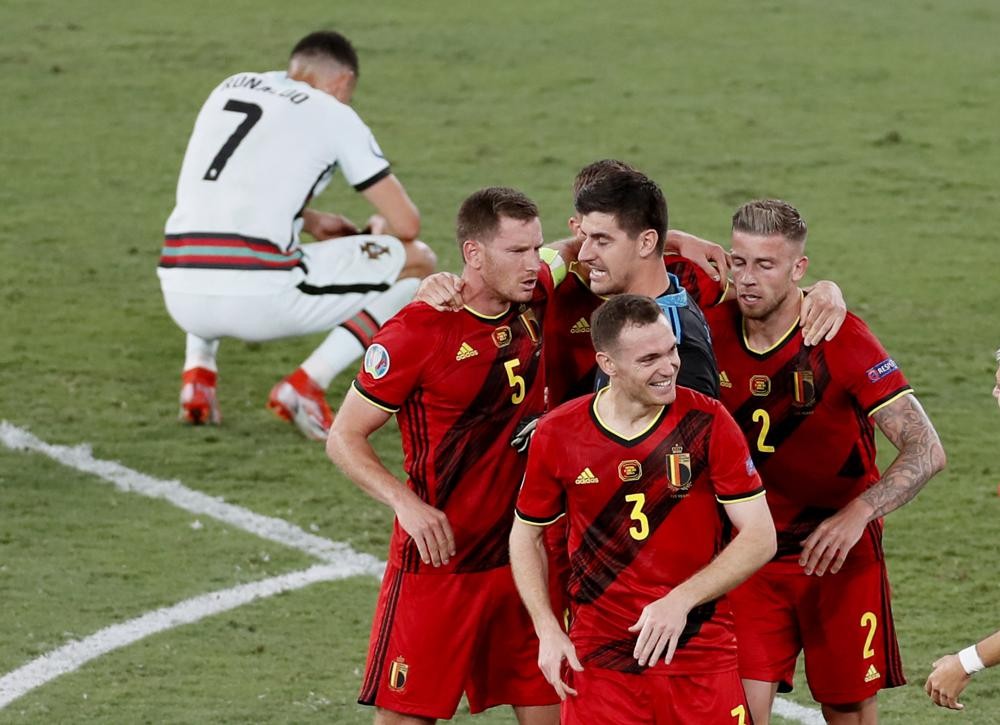 Belgium players celebrate winning 1-0 as Portugal's Cristiano Ronaldo, 7, reacts after the Euro 2020 soccer championship round of 16 match between Belgium and Portugal at La Cartuja stadium in Seville, Spain, Sunday, June 27, 2021. (Jose Manuel Vidal/Pool via AP)
