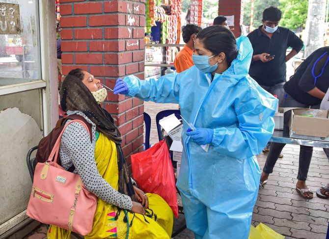 A health worker collects swab sample of a passenger for Covid-19 test, at Majestic bus stand in Bengaluru. Photograph: Shailendra Bhojak/PTI Photo