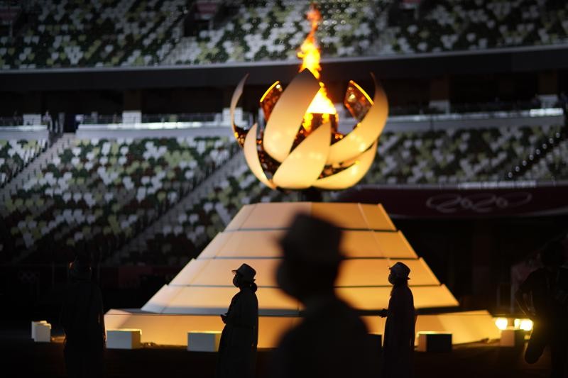 Volunteers stand as International Olympic Committee's President Thomas Bach gives a speech during the closing ceremony in the Olympic Stadium at the 2020 Summer Olympics, Sunday, Aug. 8, 2021, in Tokyo, Japan. (AP Photo/David Goldman)