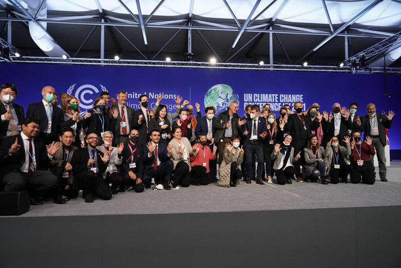 Delegates from different countries pose for a group photograph together on stage in the plenary room at the COP26 U.N. Climate Summit, in Glasgow, Scotland, Saturday, Nov. 13, 2021. Going into overtime, negotiators at U.N. climate talks in Glasgow are still trying to find common ground on phasing out coal, when nations need to update their emission-cutting pledges and, especially, on money. (AP Photo)