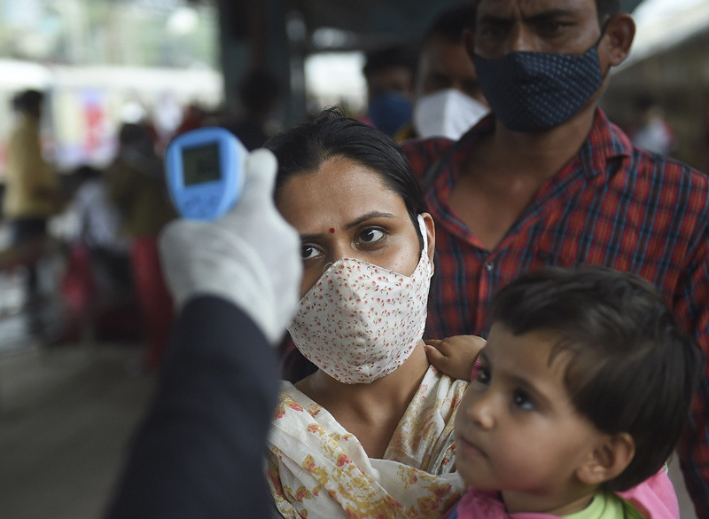 A health worker checks body temperature of a passenger as a precaution against the coronavirus, at Dadar Railway Station in Mumbai on November 30, 2021. (PTI Photo)