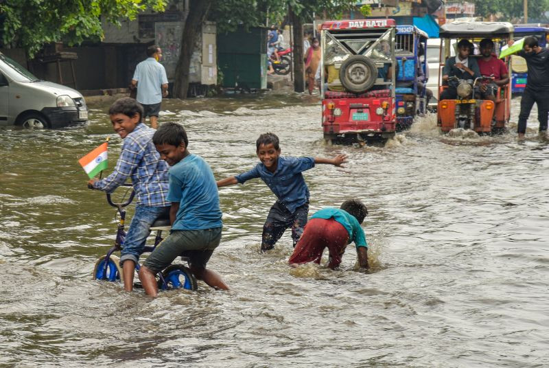 Children play in rain-water as vehicles wade through a waterlogged street after rain at Jahangirpuri area in New Delhi on August 21, 2021. (PTI File Photo)