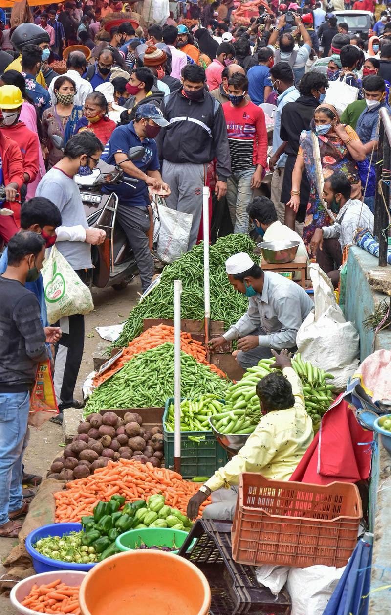 People buy vegetables at a crowded market in Bengaluru on November 28, 2021. The Karnataka government has decided to intensify surveillance and increase  the RT-PCR Covid tests at the bus stands and railway stations following reports of new COVID-19 variant Omicron in several countries and new clusters of Covid-19 infections in different districts. (PTI Photo)