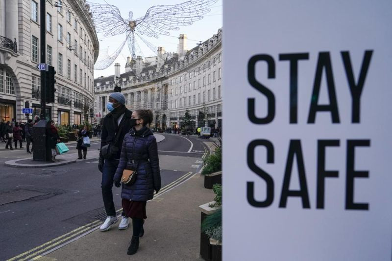 People wear face masks as they walk, in Regent Street, in London, Sunday, Nov. 28, 2021. Britain's Prime Minister Boris Johnson said it was necessary to take "targeted and precautionary measures" after two people tested positive for the new variant in England. He also said mask-wearing in shops and on public transport will be required. (AP Photo)