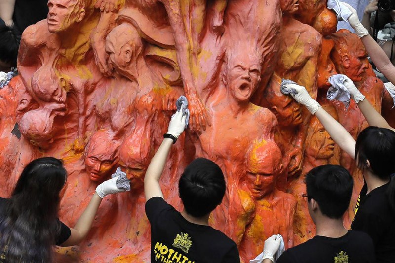 University students clean the "Pillar of Shame" statue, a memorial for those killed in the 1989 Tiananmen crackdown, at the University of Hong Kong, June 4, 2019. For Hong Kong’s pro-democracy movement, 2021 has been a year in which the city’s authorities and the central government in Beijing stamped out nearly everything it had stood for. (AP File Photo)