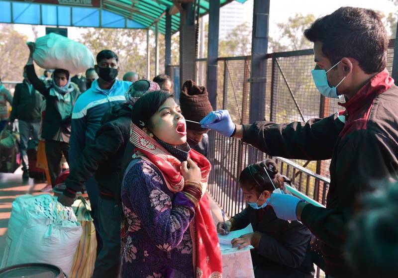 A health official takes a swab sample for COVID-19 testing  at New Delhi Railway station amid concern over rising Omicron cases, in New Delhi on December 27, 2021. (PTI Photo)