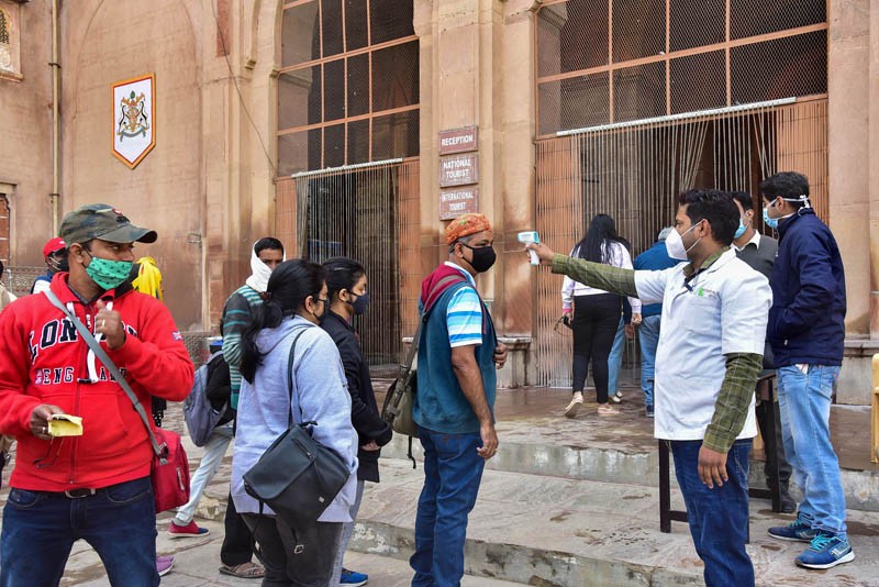 A health worker uses a temperature screening device on tourists, in wake of rise in Omicron variant of the coronavirus, at Junagarh fort in Bikaner on December 29. (PTI Photo)