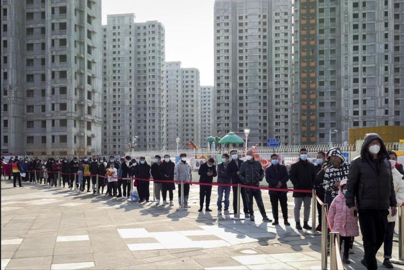 Residents wearing face masks to protect from the coronavirus line up for the coronavirus test during a mass testing in north China's Tianjin municipality, Sunday, Jan. 9, 2022. Tianjin, a major Chinese port city near the capital Beijing, began mass testing of its 14 million residents on Sunday, after a cluster of a dozen of children and adults tested positive for COVID-19, including a few with the omicron variant. (AP Photo)