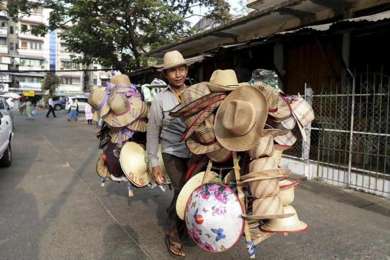 A vender carries bamboo hats for sale at a market in Yangon, Myanmar Saturday, March 21, 2020. About 1.6 million jobs were lost in Myanmar in 2021, the International Labor Organization, said in a report Friday, Jan. 28, 2022, with women suffering the biggest setbacks as work in factories, tourism and construction dwindled amid the pandemic and a military takeover. (AP File Photo)