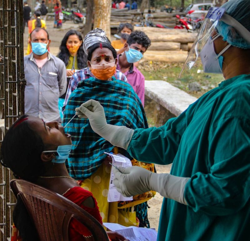 A health worker collects swab sample of a woman for COVID-19 test, at a government-run hospital near Balurghat, in South Dinajpur district on January. 11, 2022. (PTI Photo)