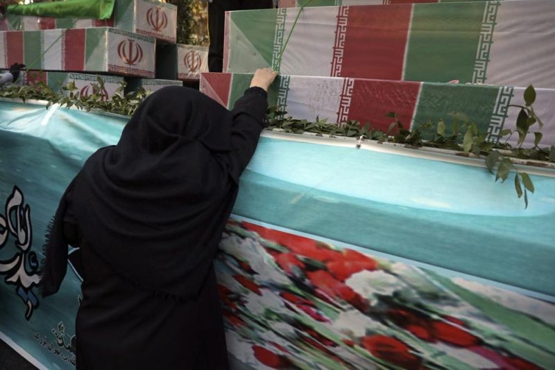 An Iranian woman mourns next to flag-draped caskets of unknown soldiers who were killed during the 1980-88 Iran-Iraq war, whose remains were recently recovered from former battlefields, during their funeral in Tehran, Iran, Thursday, Jan. 6, 2022. Thousands of mourners poured into the streets of Iranian cities on Thursday for the mass funeral of 250 victims of the war, a testament to the brutal conflict's widespread scale and enduring legacy 35 years later. (AP Photo)
