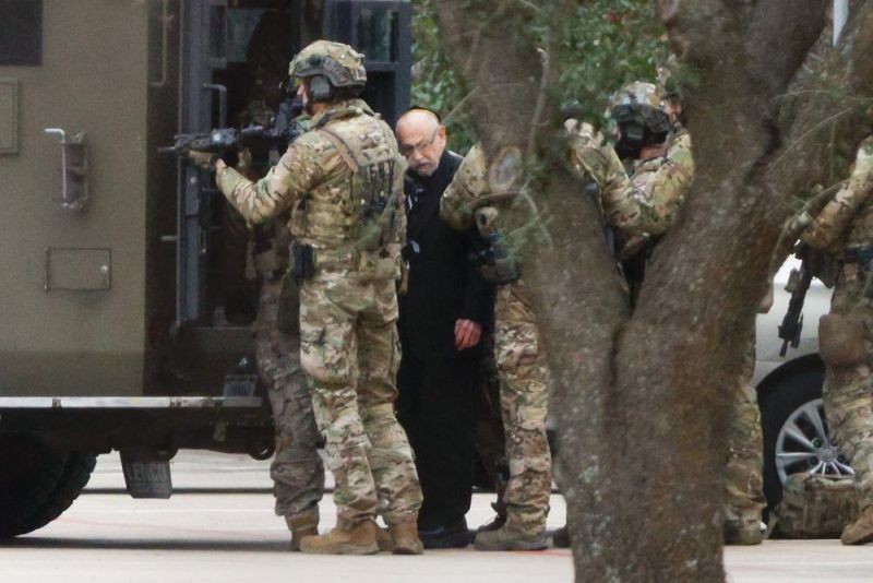 Shortly after 5 p.m., local time, authorities escort a hostage out of the Congregation Beth Israel synagogue in Colleyville, Texas, Saturday, Jan. 15, 2022. Police said the man was not hurt and would be reunited with his family. (AP Photo)