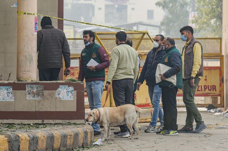 National Security Guard (NSG) and police personnel with a sniffer dog examine the nearby areas after an Improvised Explosive Device (IED) was found inside a bag, at Ghazipur flower market in New Delhi on January 14, 2022. (PTI Photo)