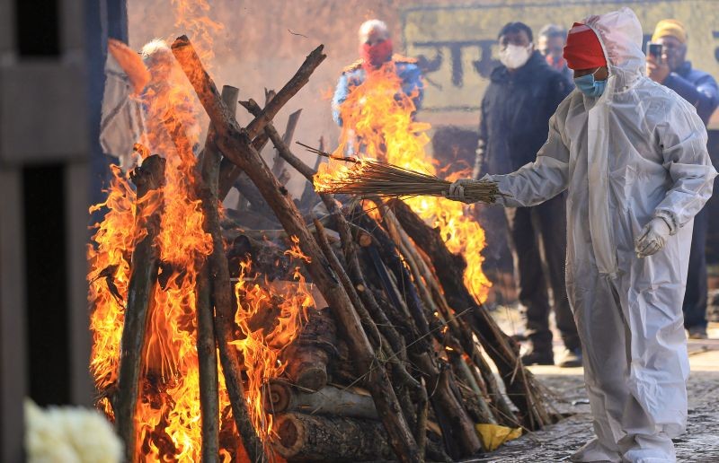 A family member wearing PPE kit performs the last rites of a COVID-19 victim, at Shastri Nagar cremation ground in Jammu on January 14, 2022. (PTI Photo)