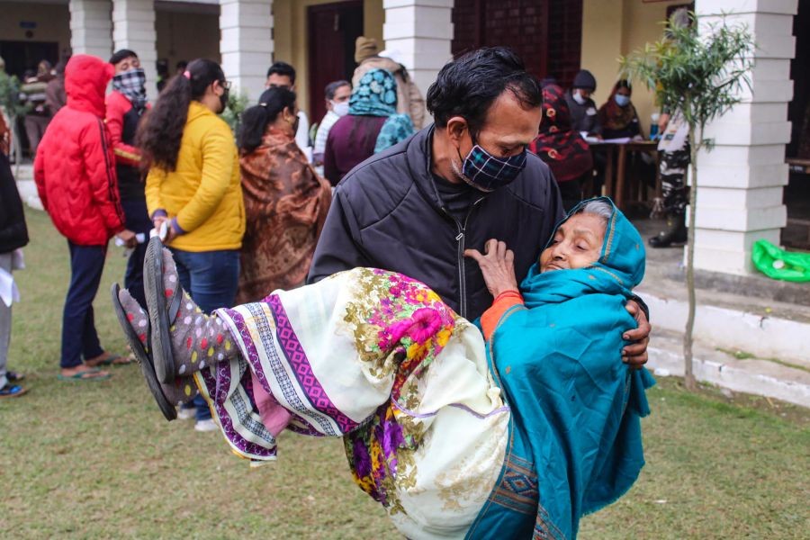 Meerut: A man carries his elderly mother in his lap after cast her vote at a polling station, during the first phase of UP Assembly elections, in Meerut, Thursday, Feb. 10, 2022. (PTI Photo)
