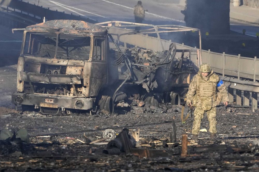 Kyiv: A Ukrainian soldier walks past debris of a burning military truck, on a street in Kyiv, Ukraine, Saturday, Feb. 26, 2022. Russian troops stormed toward Ukraine's capital Saturday, and street fighting broke out as city officials urged residents to take shelter. AP/PTI