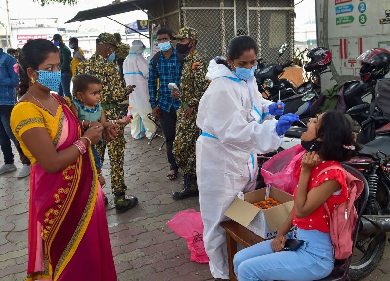 A healthcare worker collects a swab sample of a passenger for the COVID-19 test at KSRTC Bus stand, in Bengaluru. (PTI Photo)