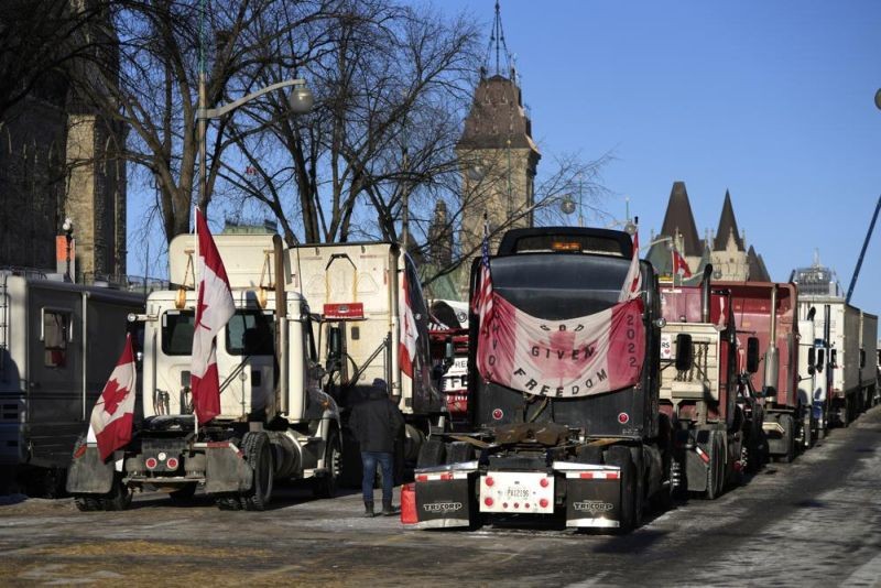 A person walks among trucks as Wellington Street is lined with trucks once again after city officials negotiated to move some trucks towards Parliament and away from downtown residences, on the 18th day of a protest against COVID-19 measures that has grown into a broader anti-government protest, in Ottawa, on Monday, Feb. 14, 2022. (AP Photo)