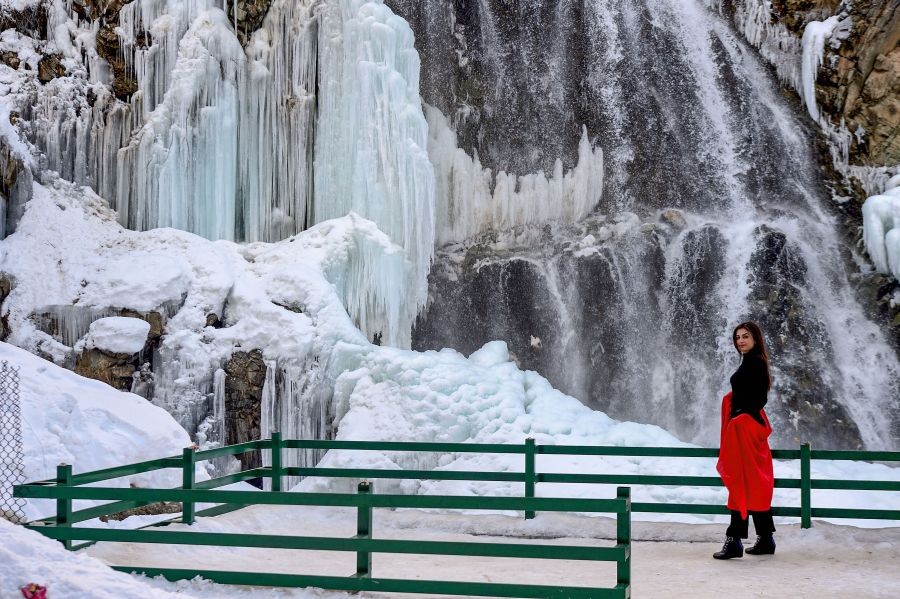 Tangmarg: A model clicks photos with the backdrop of a frozen waterfall, at the Drang area, in Tangmarg, Thursday, Feb. 10, 2022. Drang has become a popular destination for tourists who visit the Valley in winters for its frozen waterfall. (PTI Photo/S. Irfan)