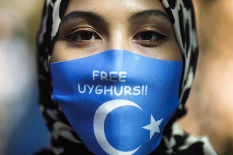 A woman wears a face mask reading 'Free Uyghurs' as she attends a protest during the visit of Chinese Foreign Minister Wang Yi in Berlin, Germany, Tuesday, Sept. 1, 2020. Experts at the U.N. labor agency have called out China on work conditions faced by Uyghurs and other Muslim minorities in the western Xinjiang region, decrying signs of “coercive measures” that deprive workers of the free choice in job-selection and calling for Beijing to provide more information about how it’s respecting their rights. (AP File Photo)