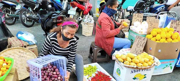 Women sell fruit and vegetables on a sidewalk in the Philippines. (ILO/Minette Rimando Photo)