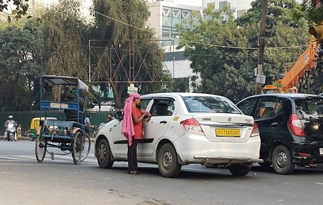 A woman holding a child begs at an intersection in New Delhi. (Ranjit Devraj/IPS Photo)